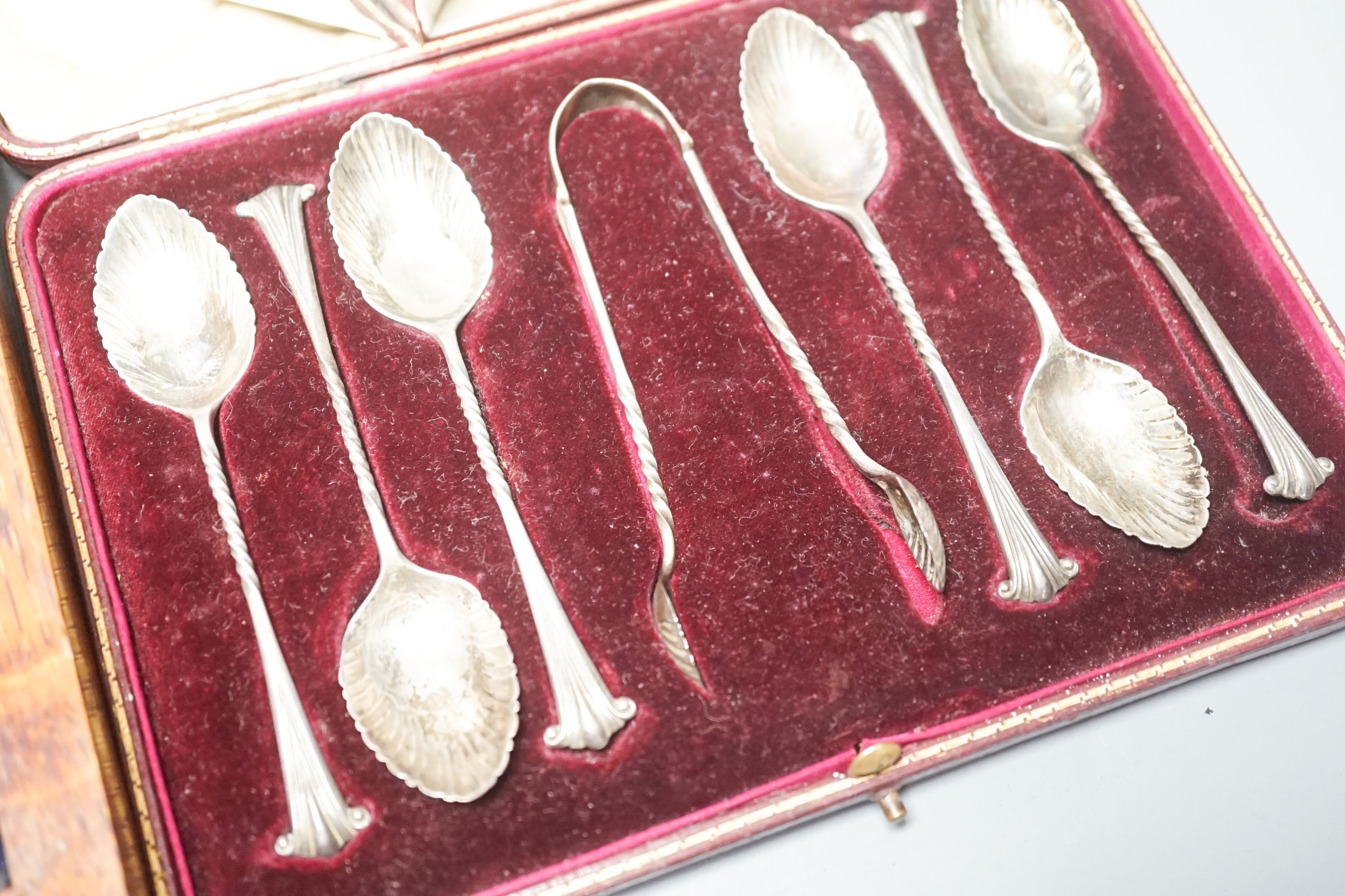 A cased set of silver teaspoons and tongs, a silver mounted cigarette case and plated part dessert service